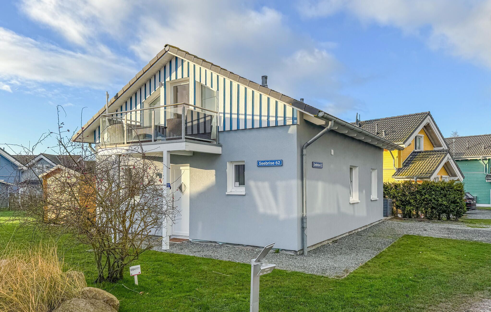A two-story house with a balcony, a visible address sign, and a small garden area.