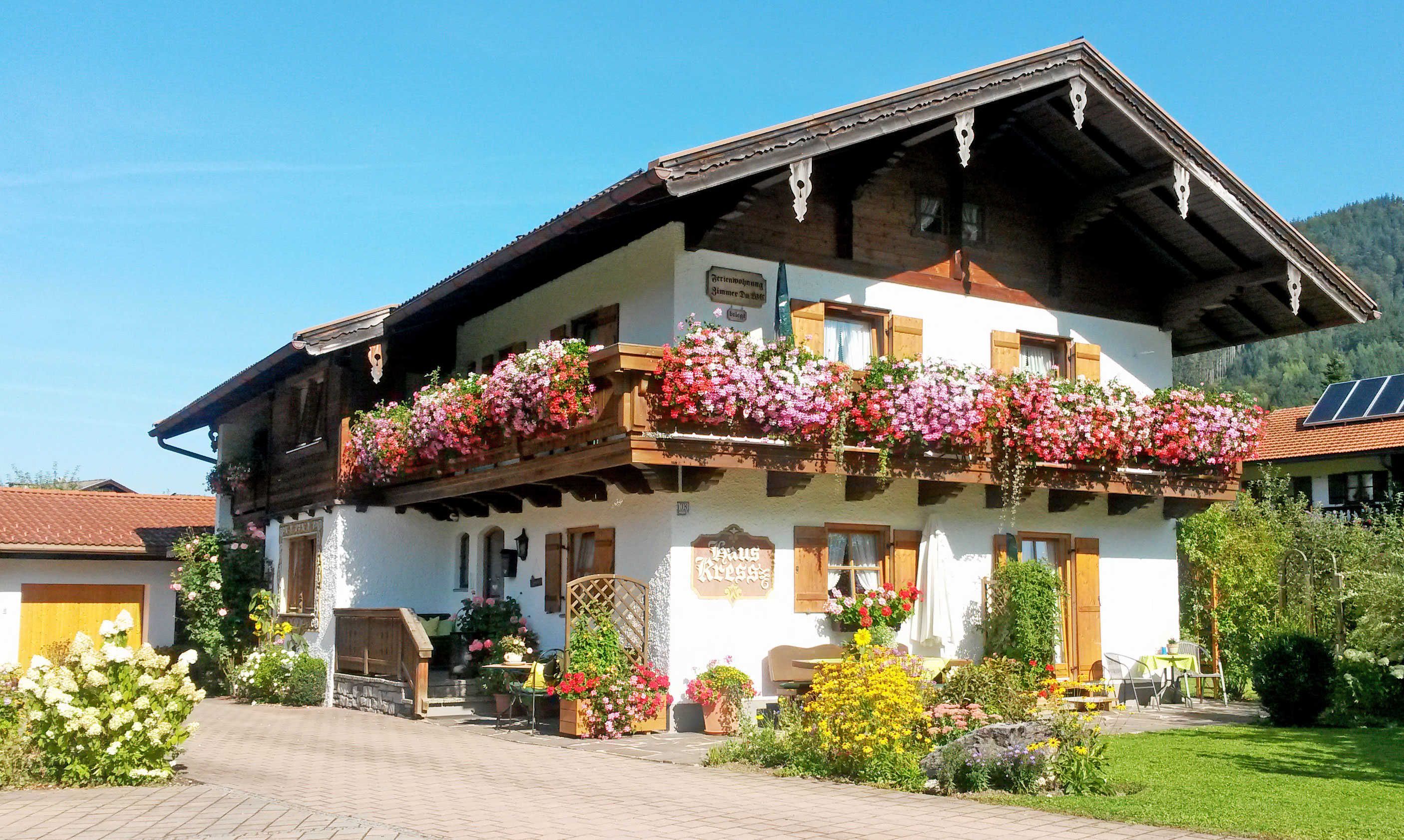Ein traditionelles Chalet mit Balkon, der mit Blumen geschmückt ist, einer Holztreppe und einem Schild, das ein Restaurant anzeigt.