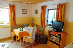 Una habitación acogedora con un sofá, una mesa con un florero, un televisor y una estantería.