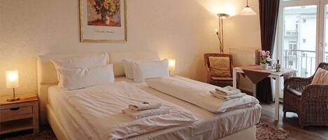 Una habitación de hotel con cama, una silla, una mesa y una ventana.