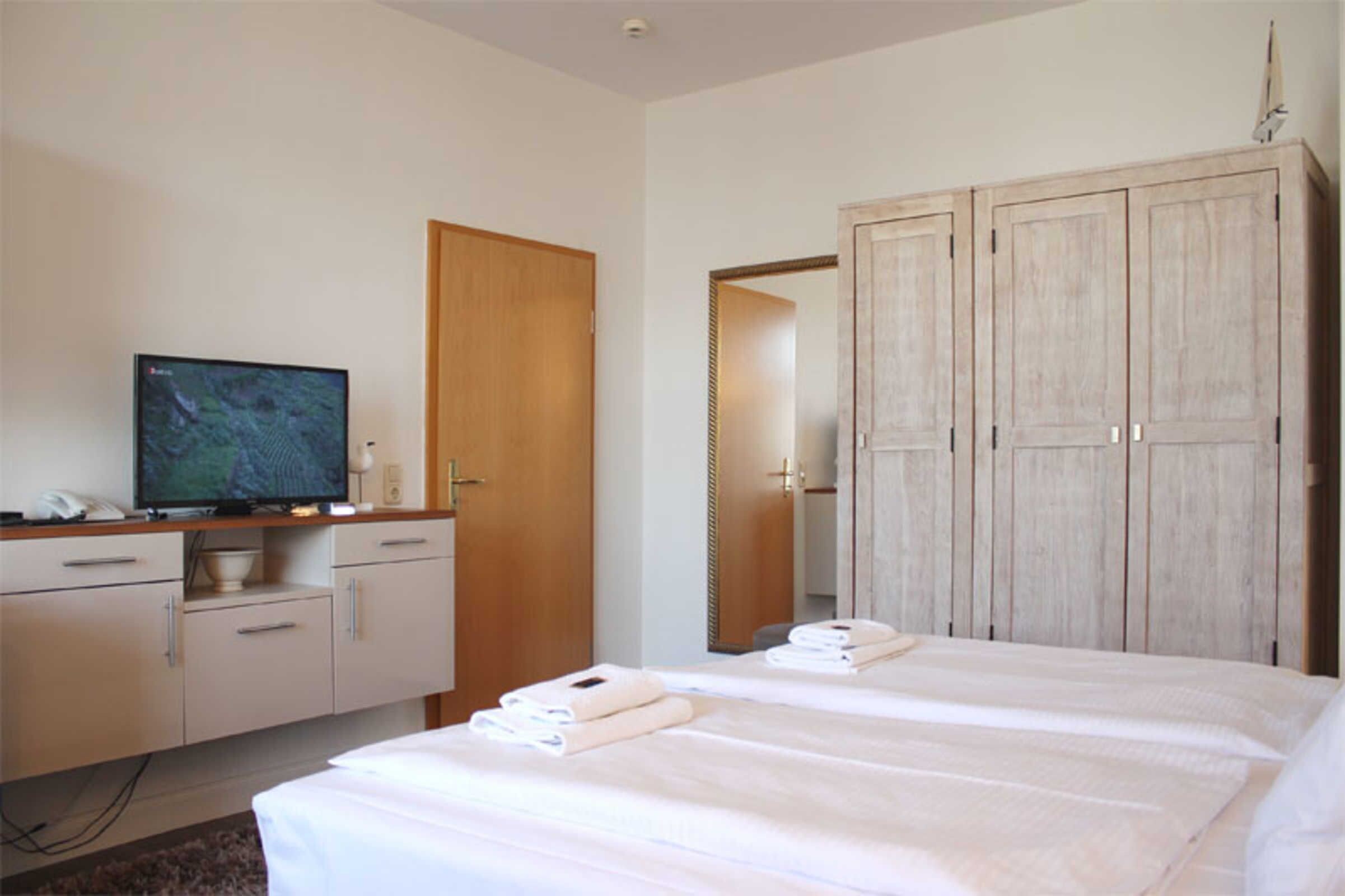 Une chambre d’hôtel équipée d’un lit, d’une télévision, d’une armoire et d’un bureau avec un téléphone.