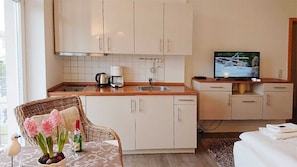 Una cucina compatta con lavello, macchina del caffè e televisore su un bancone in legno.
