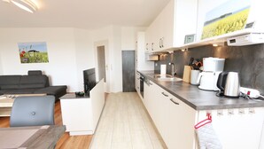 A modern kitchen with white cabinets, a grey countertop, and a coffee machine. - F: SEEMANN Apartment Whg. C14 with balcony - SEEMANN Apartment Whg. C14 with balcony - SEEMANN Apartment Whg. (Thiessow)