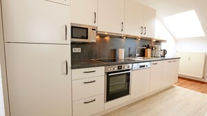 A modern kitchen with white cabinets, a built-in oven, a microwave, and a large skylight. - F: SEEMANN Apartment Whg. C14 with balcony - SEEMANN Apartment Whg. C14 with balcony - SEEMANN Apartment Whg. (Thiessow)