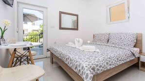 Un dormitorio con una cama, una mesita con sillas, un espejo y una ventana.
