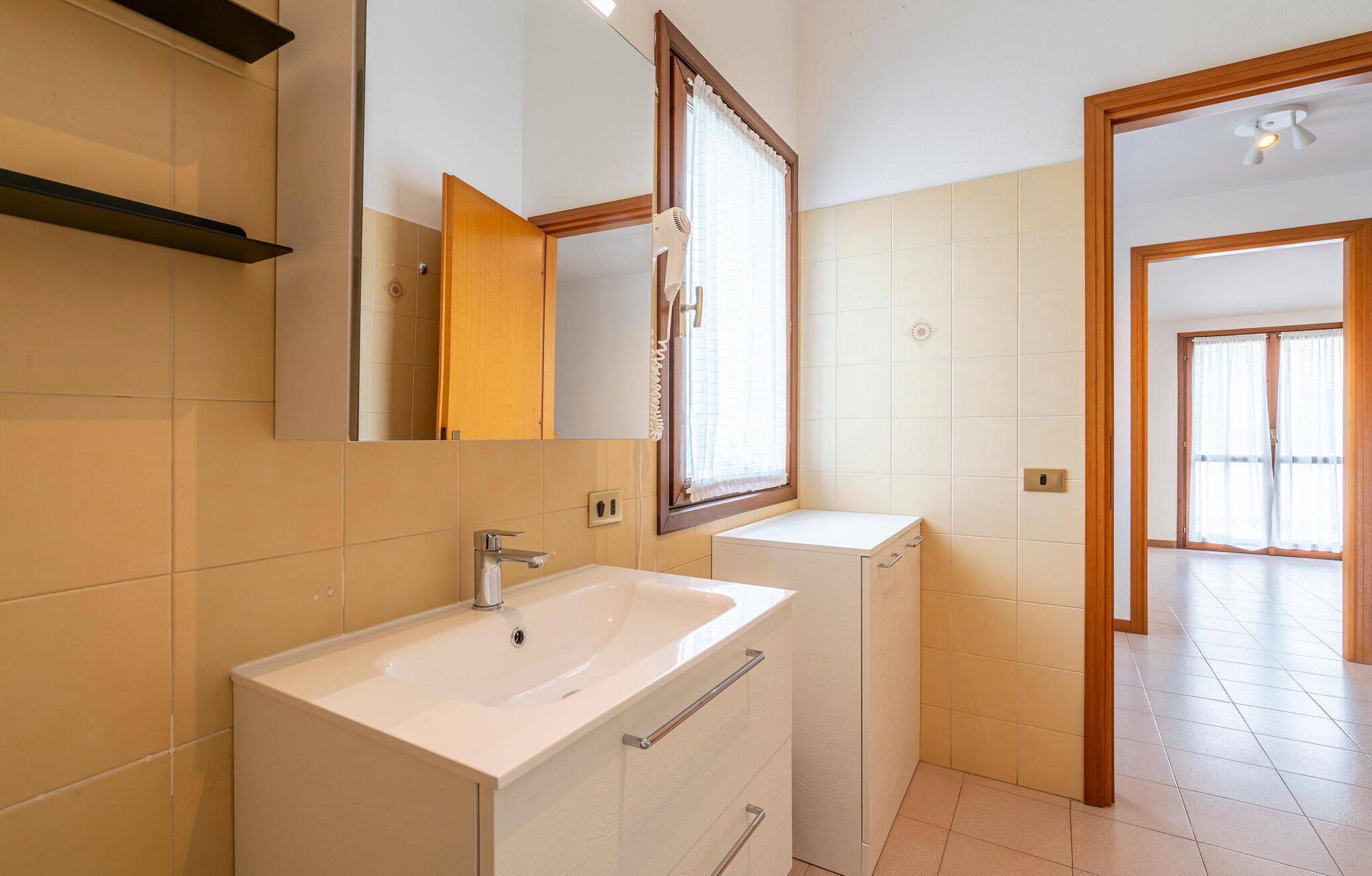 A modern bathroom with a white sink, a mirror, and a shower area.
