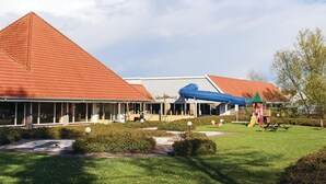 Ein Gebäude mit rotem Dach, einer blauen Rutsche und einem Picknickbereich.