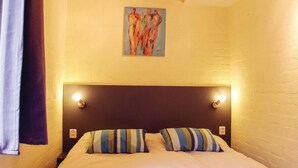 Ein Hotelzimmer mit Bett, gestreifte Kissen, einem Kopfteil mit Beleuchtung und einem Bild an der Wand.