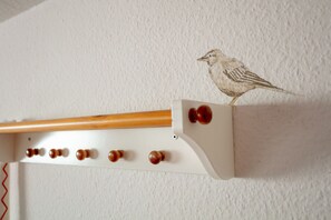 Una estructura de madera fijada a la pared, con una ilustración de un pájaro, una vara de madera y varios pomos redondos.