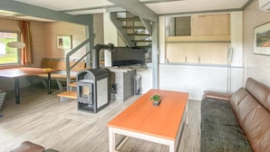 A cozy living area with a sofa, a table, a fireplace, and a staircase leading to an upper level.
