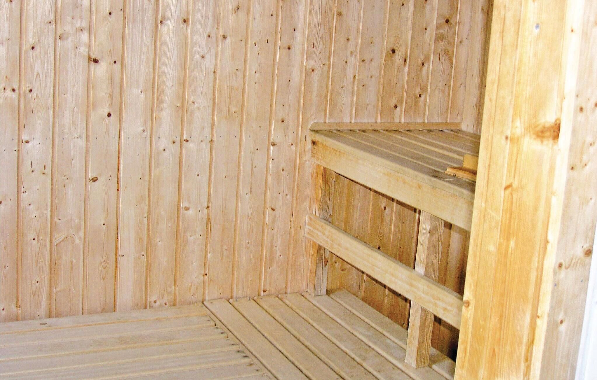 A wooden sauna with a bench and a shelf.