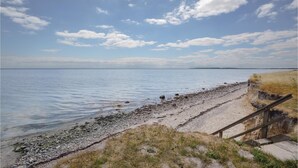 A coastal walkway with a wooden staircase leading down to the beach, surrounded by pebbles and sparse vegetation. - Awesome home in Haderslev with WiFi (Haderslev)