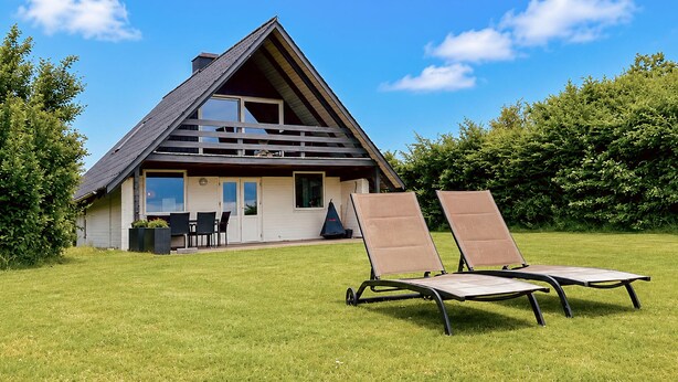 A modern house with a triangular roof, a patio with two lounge chairs, and a small table. - Awesome home in Haderslev with WiFi (Haderslev)