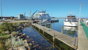 A marina with boats docked, a pier extending into calm water, and industrial buildings in the background. - Awesome home in Haderslev with WiFi (Haderslev)