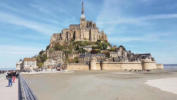 A large historic castle with a prominent tower, situated on a hill overlooking a beach. - 2 bedroom gorgeous home in La Fresnais (La Fresnais)