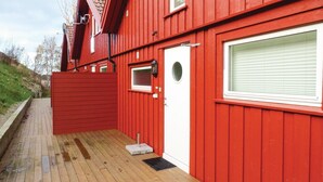 Un edificio rojo con puerta blanca, una ventana pequeña y una terraza de madera.