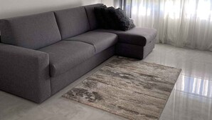 A modern living room with a grey sectional sofa, a patterned rug, and sheer curtains. - Holiday apartment with air conditioning and terrace (Kampor)