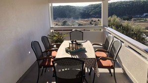 A covered outdoor dining area with a table and chairs, a view of a forested landscape, and a rustic wooden ceiling. - Holiday apartment with air conditioning and terrace (Kampor)