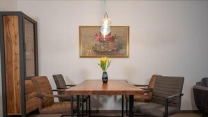 A dining area with a wooden table, black metal frame, and two chairs. A vase with flowers is on the table. - (110) 3-room apartment - lake view - apartment complex Baltic Sea (Kühlungsborn)