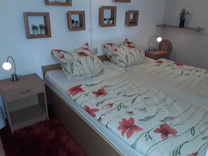 Una camera da letto con un letto, comodini, una lampada e mensole a parete con oggetti decorativi.