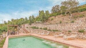 A swimming pool with a stone wall and lounge chairs, surrounded by a stone staircase and greenery. - Gorgeous home in Sperlonga -LT- (Sperlonga -LT-)