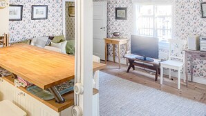 A cozy living room with a wooden dining table, a television, and a white chair. - 2 bedroom stunning home in Strängnäs (Strängnäs)