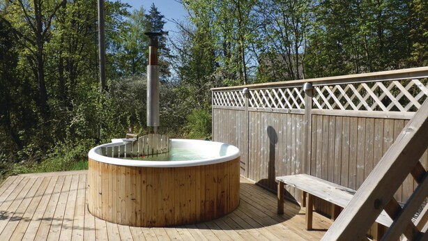 A wooden deck with a hot tub, a wooden bench, and a wooden fence. - 2 bedroom stunning home in Strängnäs (Strängnäs)