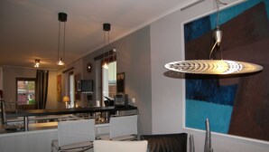 Une cuisine moderne avec un coin bar, une table à manger avec des chaises et un grand tableau abstrait accroché au mur.