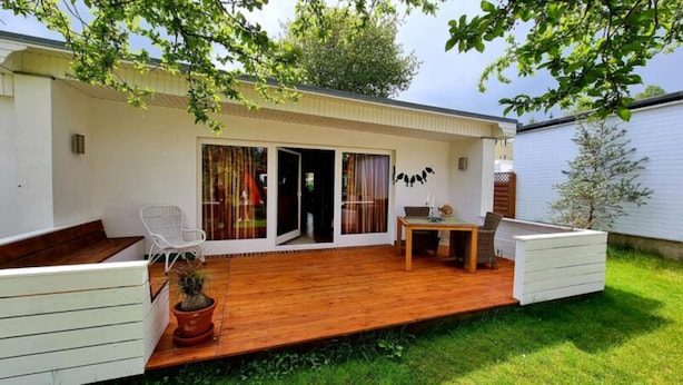 Un patio couvert avec une terrasse en bois, une table à manger, des chaises et une plante en pot.
