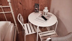 A small, round white table with a menu and a remote control on it. There are two white chairs with striped seats. - Ferienzimmer Moorhexe - Holiday room in Graal-Müritz (Graal-Müritz)