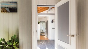 Un corridoio con soffitto in legno, vista su una sala da pranzo e una porta con pannello grigio.