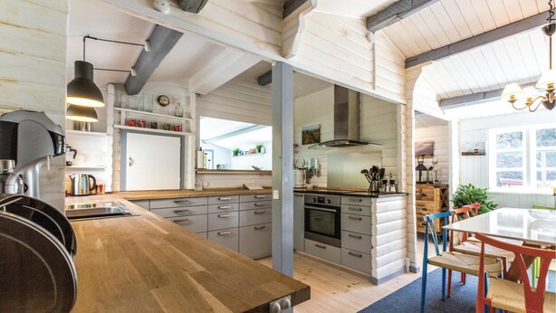 Una cucina moderna con piani di lavoro in legno, forno integrato e zona pranzo con tavolo e sedie.