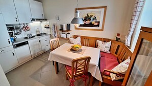 Una cocina compacta con electrodomésticos modernos, una mesa de comedor con sillas y un rincón de estar acogedor con sofá y cojines.