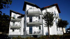 Un edificio residencial de varios pisos con balcones, techo plano y cielo despejado.