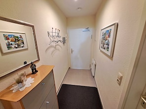 A narrow hallway with a wooden bench, a radiator, and framed photographs on the walls.