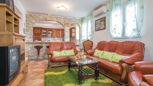 Una sala de estar con sofás de cuero, una mesa de centro y un televisor.