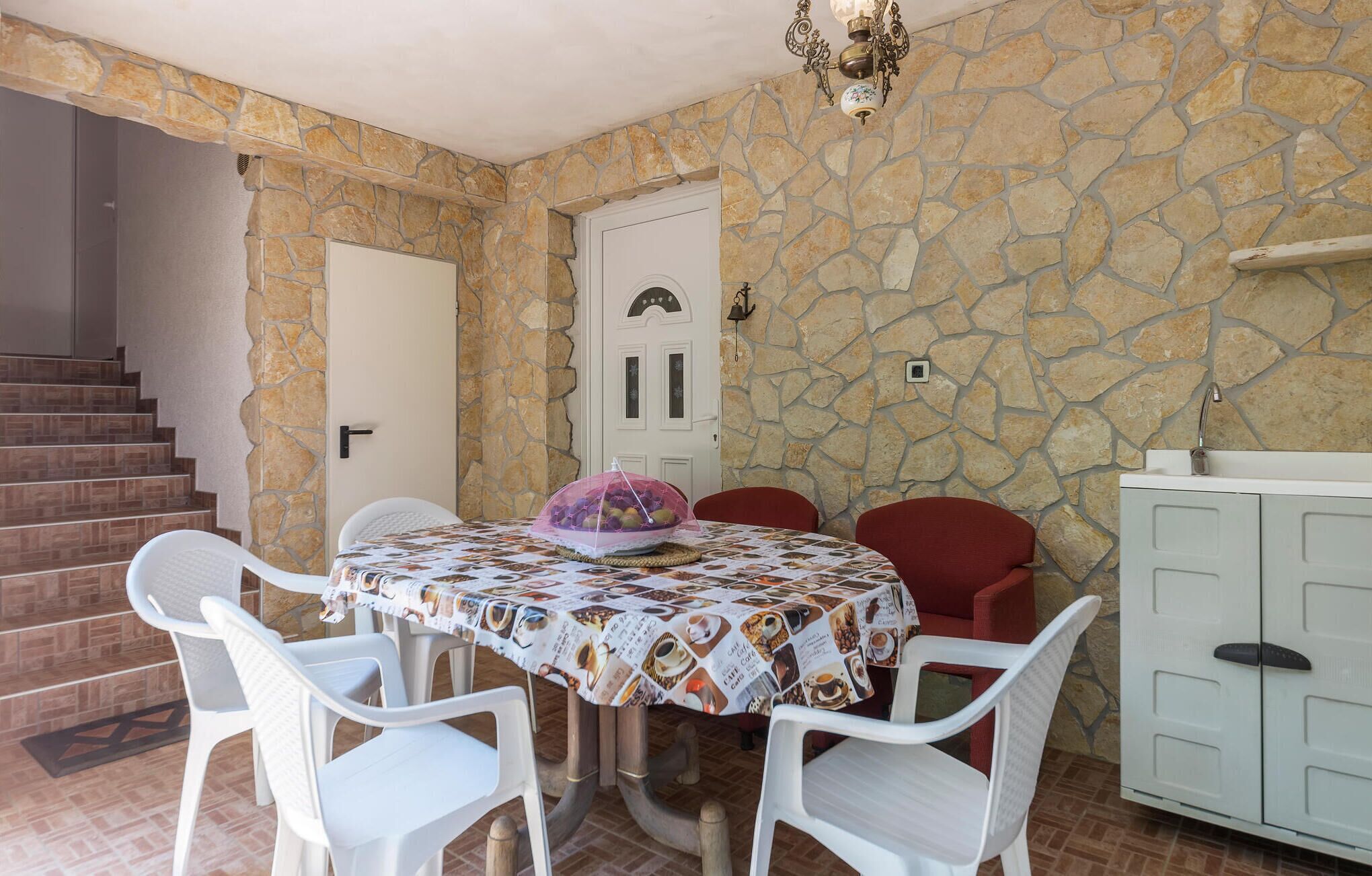 A dining area with a stone wall, a white door, and a staircase.
