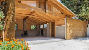 Una cabaña de madera con un porche cubierto, ventanas amplias y piso de concreto.