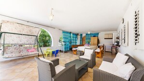 Amplia sala de estar con mobiliario de mimbre, un columpio y una cocina con estufa y armarios.