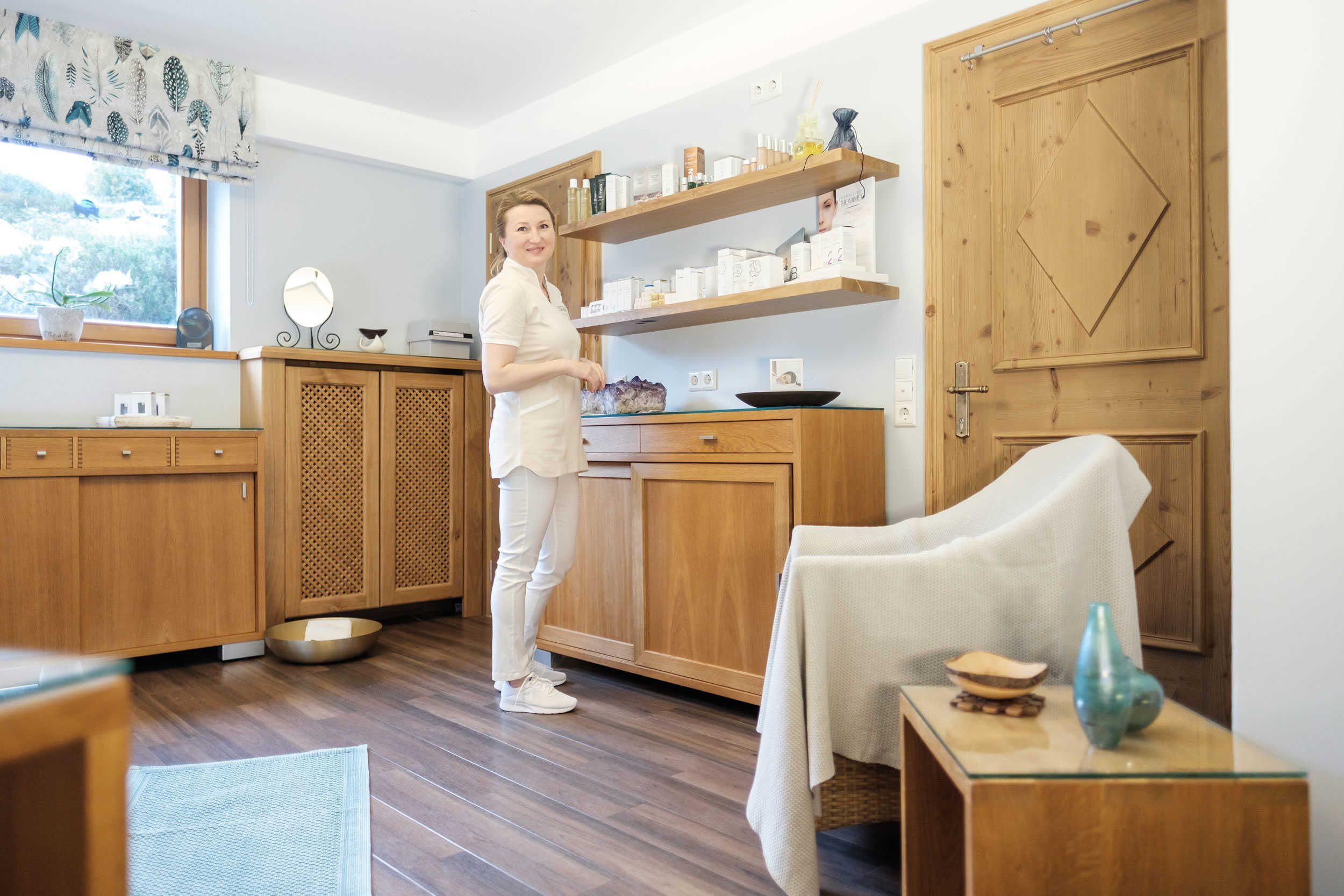 Una cocina con armarios de madera, una ventana con cortina y una persona de pie.