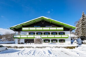 Un edificio de dos pisos con techo verde y paredes blancas, rodeado de nieve.