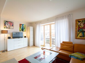 A modern living room with a sofa, a TV, and artwork on the walls. - Residence Starfish Whg S-10 .. - See-10 (Kühlungsborn)