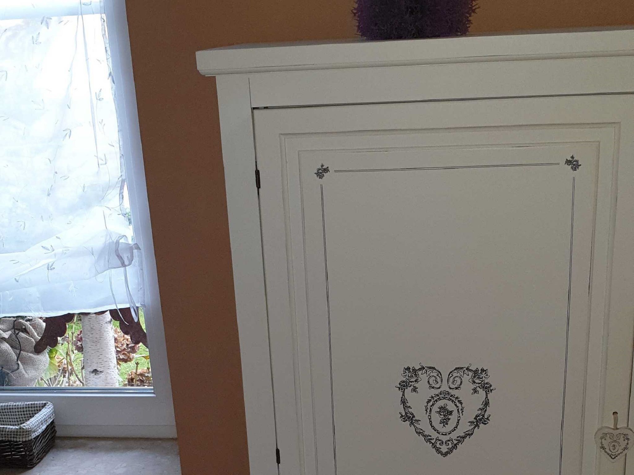 Een witte kast met een decoratief hartbeeld en een klein hartvormig object aan de rechterkant.