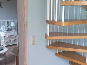 A room with a white dresser, a lamp, and a wall-mounted light switch.