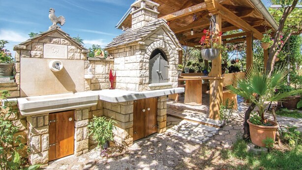A stone building with a stone chimney, a wooden pergola, and a stone bench. - Gorgeous apartment in Modrusani (Modrusani)