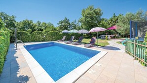 A rectangular swimming pool with a tiled edge, surrounded by lounge chairs and umbrellas. - Gorgeous apartment in Modrusani (Modrusani)