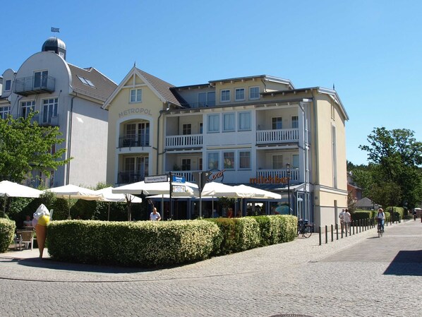 A hotel with a white facade, balconies, and outdoor seating areas.