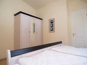 A bedroom with a bed, a wardrobe, and a door. - Metropol Whg. ME-08. - Metropol Whg. 08 (Kühlungsborn)
