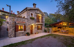 Enjoy evening gatherings in the outdoor seating area with a fire pit, surrounded by a well-maintained garden and a welcoming entrance.