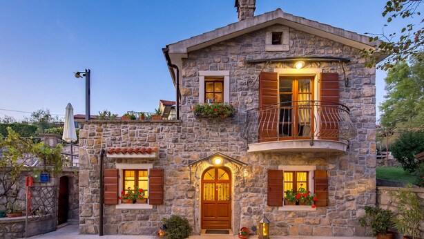 A stone building with a wooden door, windows with shutters, and a balcony with a railing. - Gorgeous home in Poljane with sauna (Poljane)